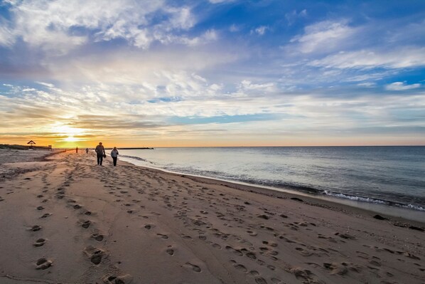 A beach with footprints and a sunset in the background.