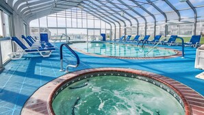 A covered swimming pool area with lounge chairs and a hot tub. - Oceanfront 1-Bedroom Condo w/ Balcony Views (Dennis Port)