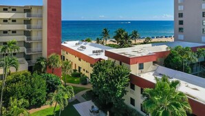 Un hotel con terraza en la azotea, palmeras y vistas al océano.