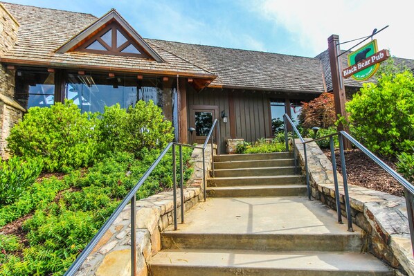 A building with a stone staircase leading to a wooden door, surrounded by greenery.