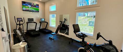 A gym with treadmills, stationary bikes, and a rowing machine.
