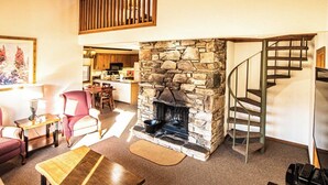 A living room with a stone fireplace, a dining area, and a staircase. - Mountain Retreat w/ Pools & Fireplace (Lake Lure)