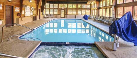 A large indoor swimming pool with a wooden interior, a lifeguard chair, and a no diving sign.
