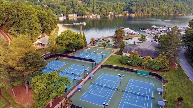 A tennis court complex with multiple courts, a parking area, and a view of a lake with boats. - Mountain Retreat w/ Pools & Fireplace (Lake Lure)