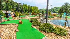 A miniature golf course with a green putting surface, a water hazard, and a rocky border. - Mountain Getaway | Pools, Trails & More! (Lake Lure)