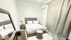 A hotel room with a bed, bedside tables, a nightstand, a mirror, a window with curtains, and a door with a lock. - 2-bedroom villa in fabulous Marrakech with WiFi, AC (Marrakech)