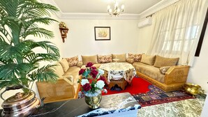 A living room with a sofa set, a coffee table with flowers, a chandelier, and a patterned rug. - 2-bedroom villa in fabulous Marrakech with WiFi, AC (Marrakech)