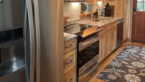 Una cocina moderna con armarios de madera, electrodomésticos de acero inoxidable y un tapete estampado.
