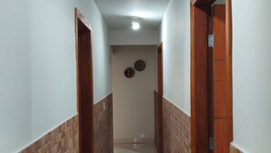 A hallway with a tiled floor, wooden doors, and a ceiling light.