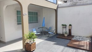 A patio area with a table and chairs, a blue umbrella, and potted plants.