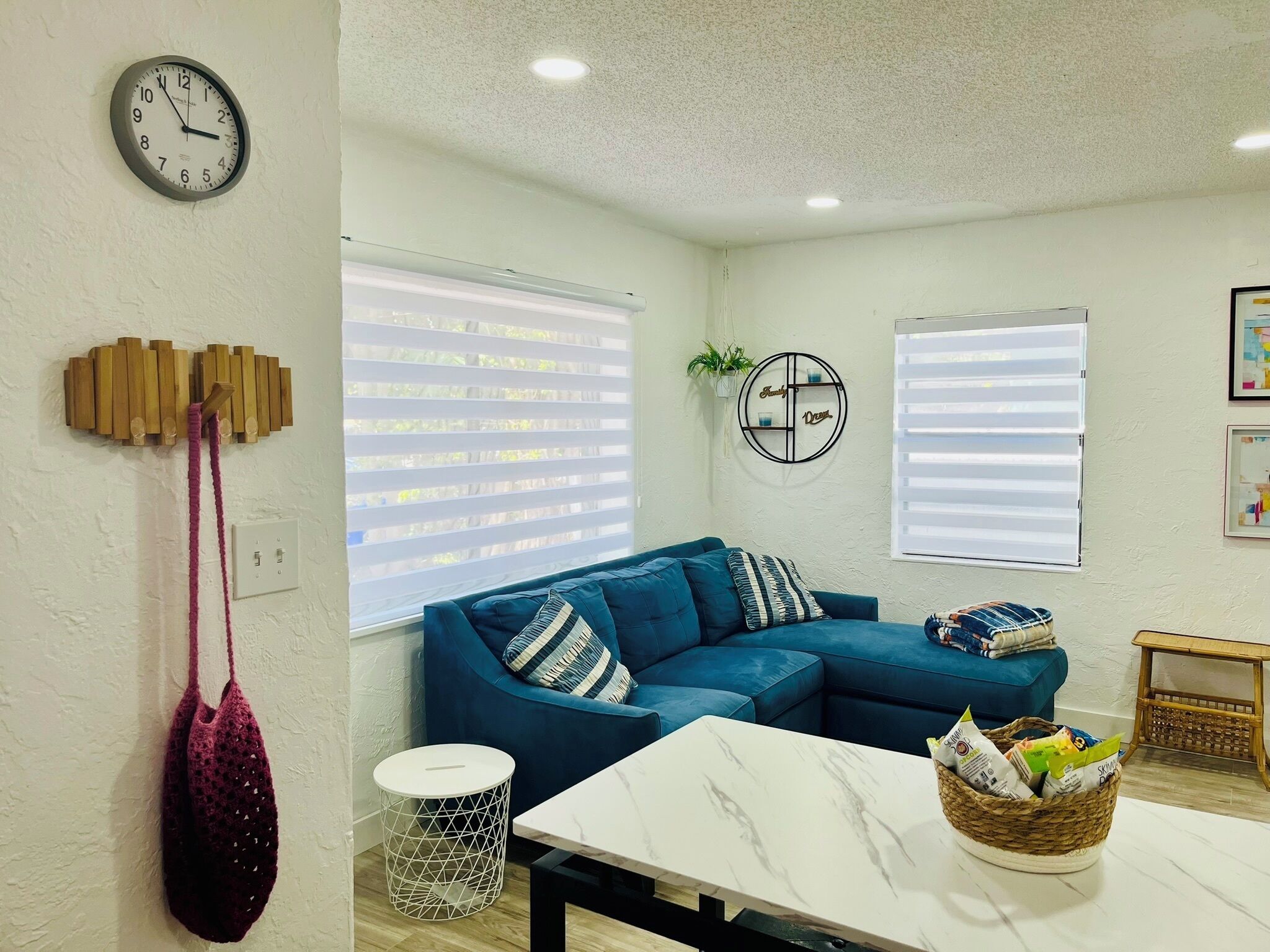 A living room with a blue sofa, a white table, and a clock on the wall.