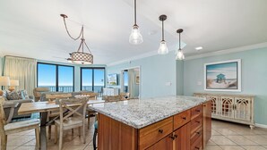 A spacious kitchen with a large island, wooden cabinets, and pendant lighting. - Phoenix X 803 | Beachfront | Next to Flora-Bama | Pools & Hot Tubs | My Beach Getaways (Orange Beach)