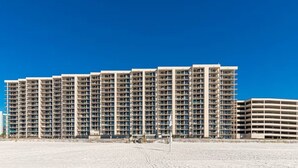 A large, multi-story hotel with numerous balconies and a flat roof. - Phoenix X 803 | Beachfront | Next to Flora-Bama | Pools & Hot Tubs | My Beach Getaways (Orange Beach)