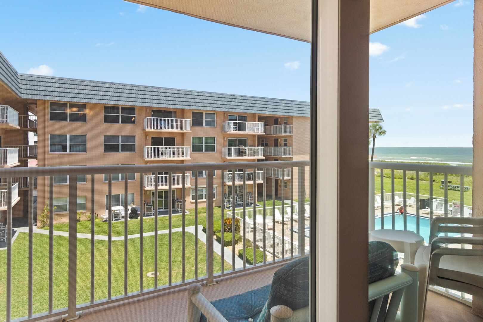 A balcony with a view of a building with multiple balconies and a swimming pool.