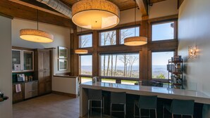 A modern kitchen with a large island, bar stools, and large windows offering a view of the outdoors. - Calico Haven at BRMC | Hot Tub, Views, Pool (Boone)