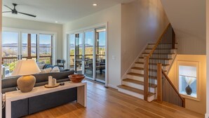 A spacious living room with a modern sofa, a wooden coffee table, and a view through large sliding glass doors to an outdoor deck. - Calico Haven at BRMC | Hot Tub, Views, Pool (Boone)