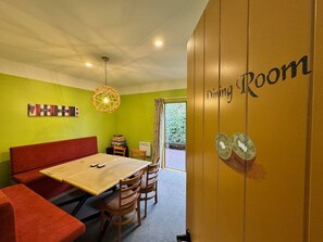 Comedor con mesa, sillas, un sofá rojo y una pared con un cartel que dice 'Dining Room'.