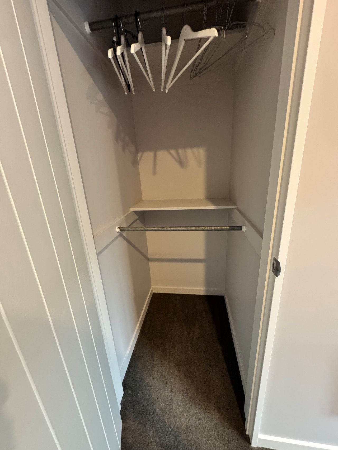 Ein kleiner, schmaler Kleiderschrank mit einer Kleiderstange.