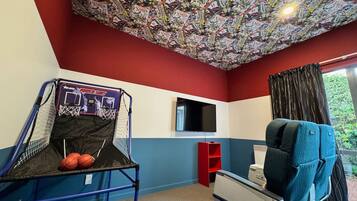 A room with a basketball hoop, a television, and a window with curtains.