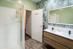 A bathroom with a white vanity, a large mirror, and a door labeled "Bathroom".