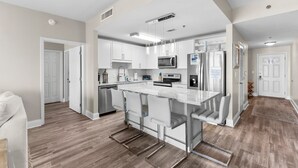 A modern kitchen with white cabinets, stainless steel appliances, and a central island with bar stools.