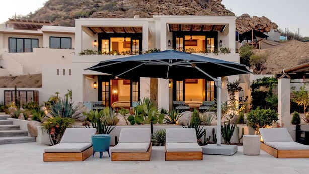 A modern house with a pool, outdoor seating, and a mountain backdrop.