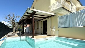 Een zwembad met een overdekt gedeelte, een balkon en een omheining.