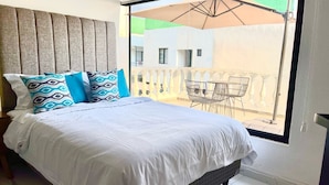 A bedroom with a bed, pillows, a window, and a balcony with chairs. - Casa Mayor (Tenancingo)