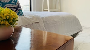 A hotel room with a bed, a wooden nightstand with a vase of yellow flowers, a white curtain, and a TV mounted on the wall. - Casa Mayor (Tenancingo)