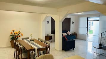 Amplia sala de estar con mesa de comedor, sofá y una escalera que conduce a otro nivel.