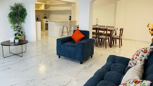 A modern living room with a sofa, a dining area with chairs, and a kitchen in the background. - Casa Mayor (Tenancingo)