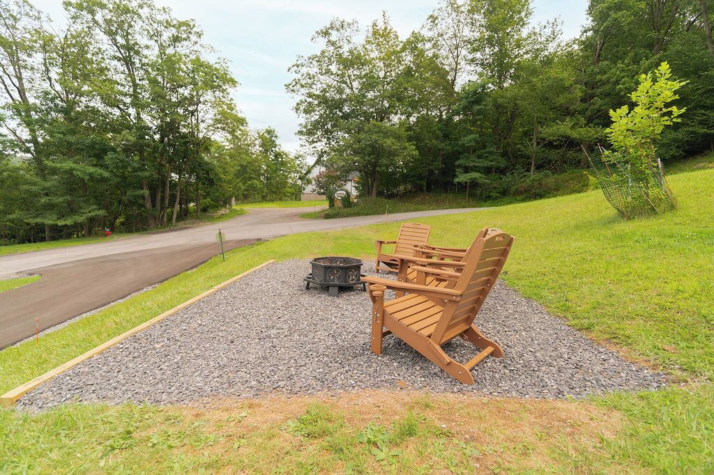 Een grindterras met houten Adirondack-stoelen en een vuurkuil.