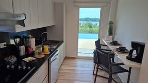 A modern kitchen with a black countertop, stainless steel appliances, and a view of a pool and greenery outside. - Two-bedroom ocean view apartment with private pool near hotel facilities (Boca Chica)