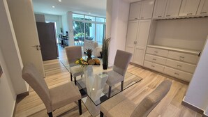 A modern dining area with a glass table, two chairs, and a centerpiece of fruits and flowers. - Two-bedroom ocean view apartment with private pool near hotel facilities (Boca Chica)