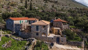 A stone building with a red-tiled roof, surrounded by greenery and a hillside. - Charming 2-bedroom apartment with WiFi, AC in lovely Nomitsi (Nomitsi)
