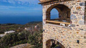 A stone building with a wooden balcony overlooking a coastal landscape. - Charming 2-bedroom apartment with WiFi, AC in lovely Nomitsi (Nomitsi)