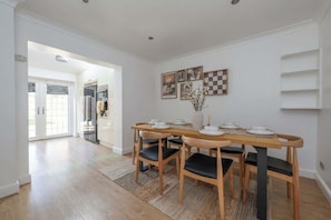 Un comedor con una mesa de madera, sillas negras y una pared blanca adornada con cuadros.