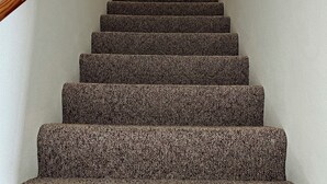 A carpeted staircase with a wooden handrail leading to a white door. - Timberside - A Getaway for the Whole Group (Dyersville)