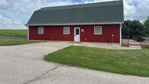 A red single-story building with a grey roof, a white door, and a small porch area. - Timberside - A Getaway for the Whole Group (Dyersville)