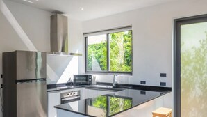 A modern kitchen with a central island, stainless steel appliances, and a large window with a view of greenery. - Experience serene sea views, private pool, and tropical luxury in this stunning 3-bedroom villa. (Ko Samui District)