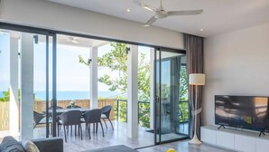 A modern living room with a large TV, a sofa, and a dining area with chairs. - Experience serene sea views, private pool, and tropical luxury in this stunning 3-bedroom villa. (Ko Samui District)