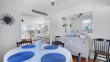 A dining area with a round table, blue placemats, and a ceiling fan.
