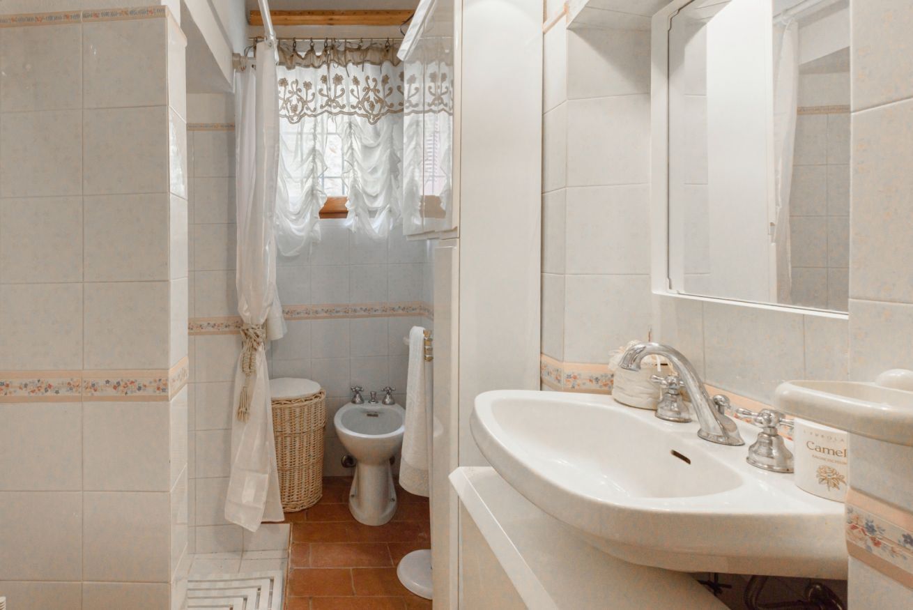 Une salle de bain avec un lavabo blanc, un miroir, un bidet et un rideau de douche.