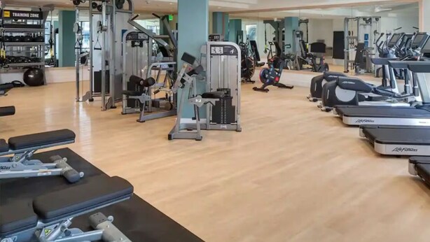 A gym with various exercise equipment including treadmills, weight machines, and free weights.