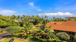 A tropical resort with lush greenery, palm trees, and a red-roofed building.