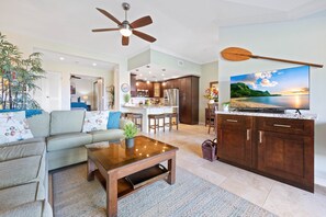 Una sala de estar con un sofá, una mesa de centro y un televisor sobre un mueble de madera.