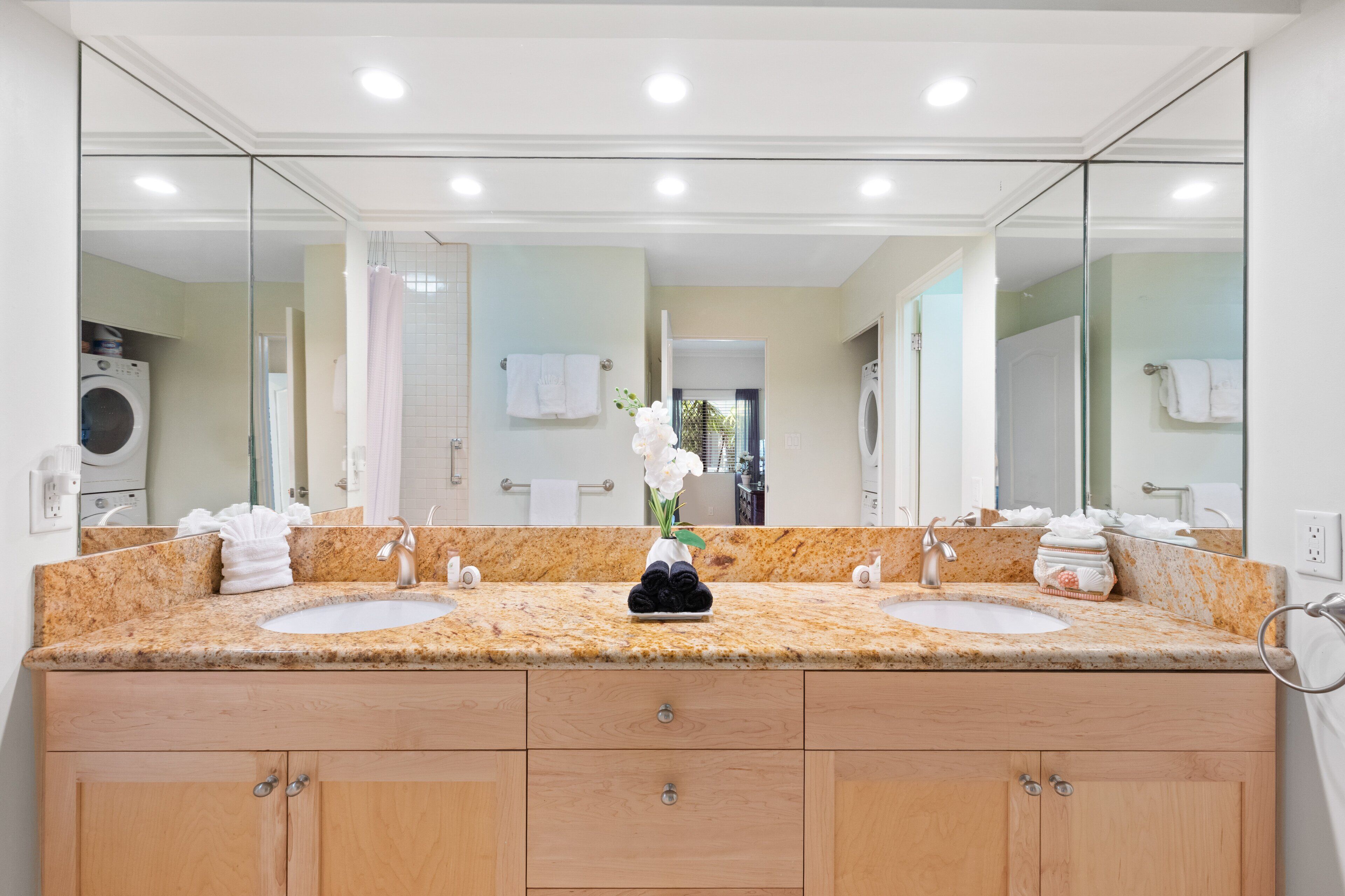 A bathroom with two sinks, a large mirror, and wooden cabinets.