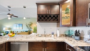 A kitchen with dark wooden cabinets, a white marble countertop, and a built-in dishwasher.