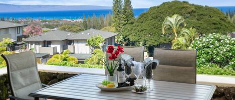 A patio table with chairs, a wine bottle, and a plate of food.