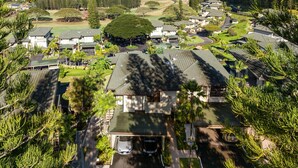 An aerial view of a residential area with houses, a golf course, and a view of the ocean.